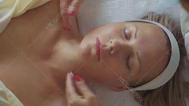 Young beautiful woman getting a cosmetic facial mask at luxury spa salon closeup