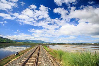 Railway Track by Water Rice Fields Vanishes into Space
