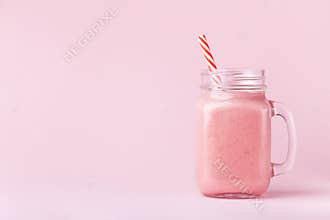 Strawberry smoothie or milkshake in mason jar on pink pastel background. Healthy food for breakfast and snack.