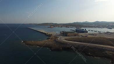 Flying over water towards port docks, containers, cargo ships.