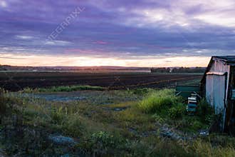 Dramatic ultra violet summer sunset over farm and shanty