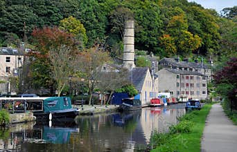 The canal and marina in hebden bridge with boats on the water, towpath and surrounding hillside trees
