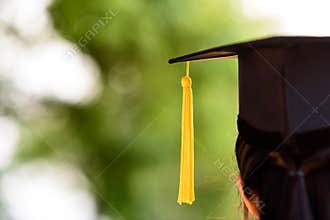 Behind photo of university graduate wears gown and black cap, ye