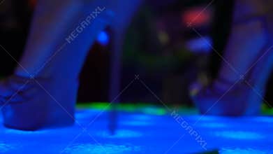 Strip girl feet in high heel shoes dancing on stage, go-go show in night club