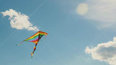A colored kite in the blue sky. Slowed-down shooting of a kite developing against a blue sky and white clouds