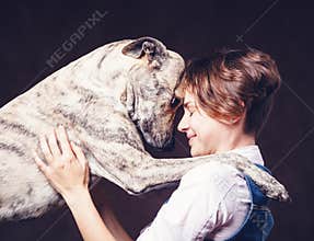 Beautiful young woman with a funny shaggy dog on a dark background. Love, care, friendship