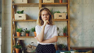 Portrait of upset young woman looking at camera and expressing negative emotions standing inside modern loft style