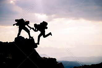 Climber reaches out to his partner by helping each other.leading climbers;Team work, life goals and self improvement concept
