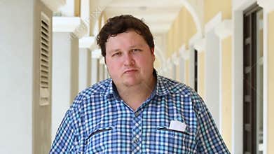 Portrait of man dancing and looking at camera. Face of a fat man wearing plaid shirt outdoor.