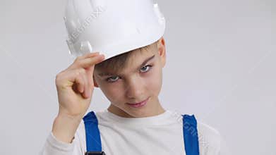 Headshot portrait of confident little foreman saluting touching hard hat looking at camera. Close-up face of handsome