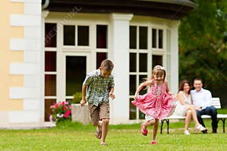 Family sitting and playing in front of their home