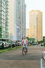 Adult man in bright casual clothes is riding a bicycle on the street and smiling. Happy man rides a bicycle on a shering bicycle