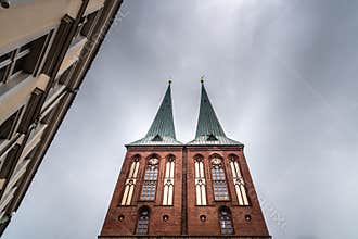 Low angle view of St. Nicholas Church towers against sky. Cloudy day of summer in Berlin
