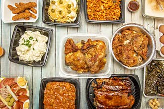 Dishes of food prepared in a home service kitchen. Roast chickens, bbq ribs, roasted green peppers, aioli potatoes, crumbs,