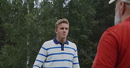 Young handsome man in light stylish clothes talking to elderly gray-haired man