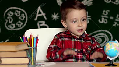 Cute boy doing homework, coloring pages, writing and painting. Children paint. Kids draw. Preschooler with books at home
