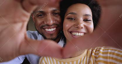 African couple faces looking through joined fingers making heart shape