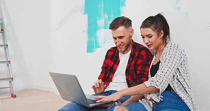 Close up of happy Caucasian young married couple man and woman sitting on the floor