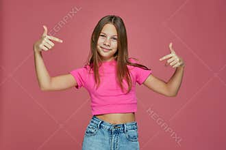 Cool confident child girl pointing to herself, proud of own success, gesturing like a rapper on pink studio background