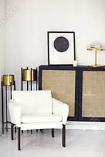 Black wooden commode with framed star map poster, lamp and candle in minimalist room interior