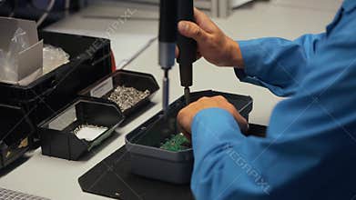 Worker in electronics manufacturing soldering a component