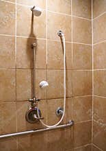 A bathroom with handicapped railings and brown tiles on the wall