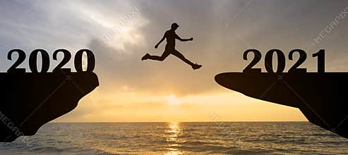 Abstract happy new year 2021 concept with silhouette man jumping from 2020 to 2021