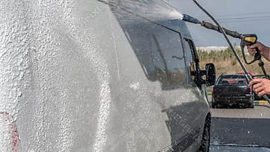 Car wash a car, a man washes a car, a man washes away dirt from a truck.