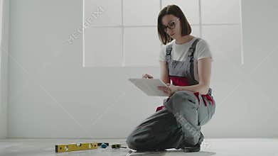 Young woman builder with dark hair works on project on floor