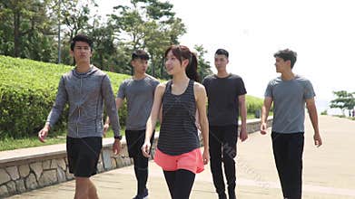 Young asian adults walking chatting in park after exercising