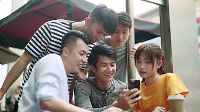 Group of young asian adults looking at cellphone together happy and smiling
