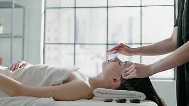 Beautician does facial massage to young woman client