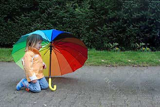 Toddler girl with  umbrella in rainbow colors
