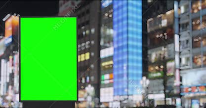 Green screen billboard on street with neon lights and advertising banners at night, Tokyo, Japan