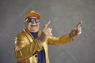 Funny senior man in golden jacket, baseball cap and chain necklace dancing and having fun