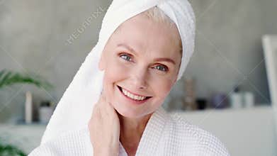 Happy smiling mid age woman looking at camera touching face.