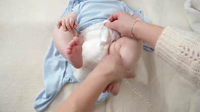 Closeup of changing diapers and changing clothes of little baby boy on bed. Concept of parenting ,baby hygiene and child