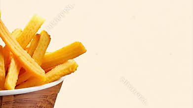 Growing pile of french fries accumulates on a white background, popular fast food snack.