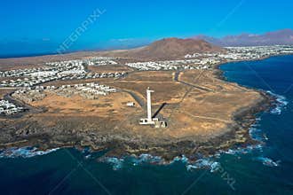 Lighthouse on the rocky cliffs, the Faro de La Pechiguera. View of the holiday resort of Playa Blanca