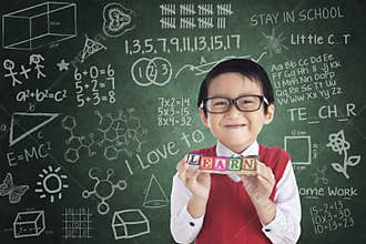 Cheerful boy student holding LEARN block