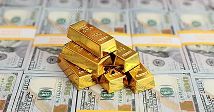 Banker puts shiny gold ingots onto dollar bills packs