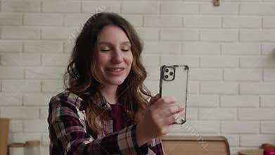 A woman is taking a selfie with her smartphone in a warm and inviting home environment
