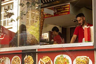 Workers in the cafeteria can be seen trying to complete all orders on time. Budapest, Király utca during the day in summer.