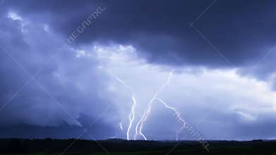 Dramatic lightning strikes illuminate stormy skies over the mountains at night