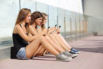 Group of three teenager girls typing on the mobile phone