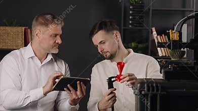 A young guy mechanical engineer uses digital calipers and measures the parameters of red plastic funnel. A middle aged