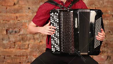 Accordion in hand of man in red shirt near wall