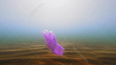 A purple package floats in the open ocean. Underwater photography. Pollution of the planet with plastics and human waste