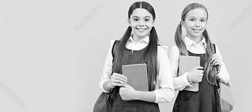 School girls friends. Happy kids in fomal uniforms with study books carry school bags. Portrait of schoolgirl student