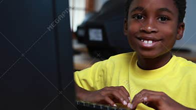 Little boy smiling at camera during computer class